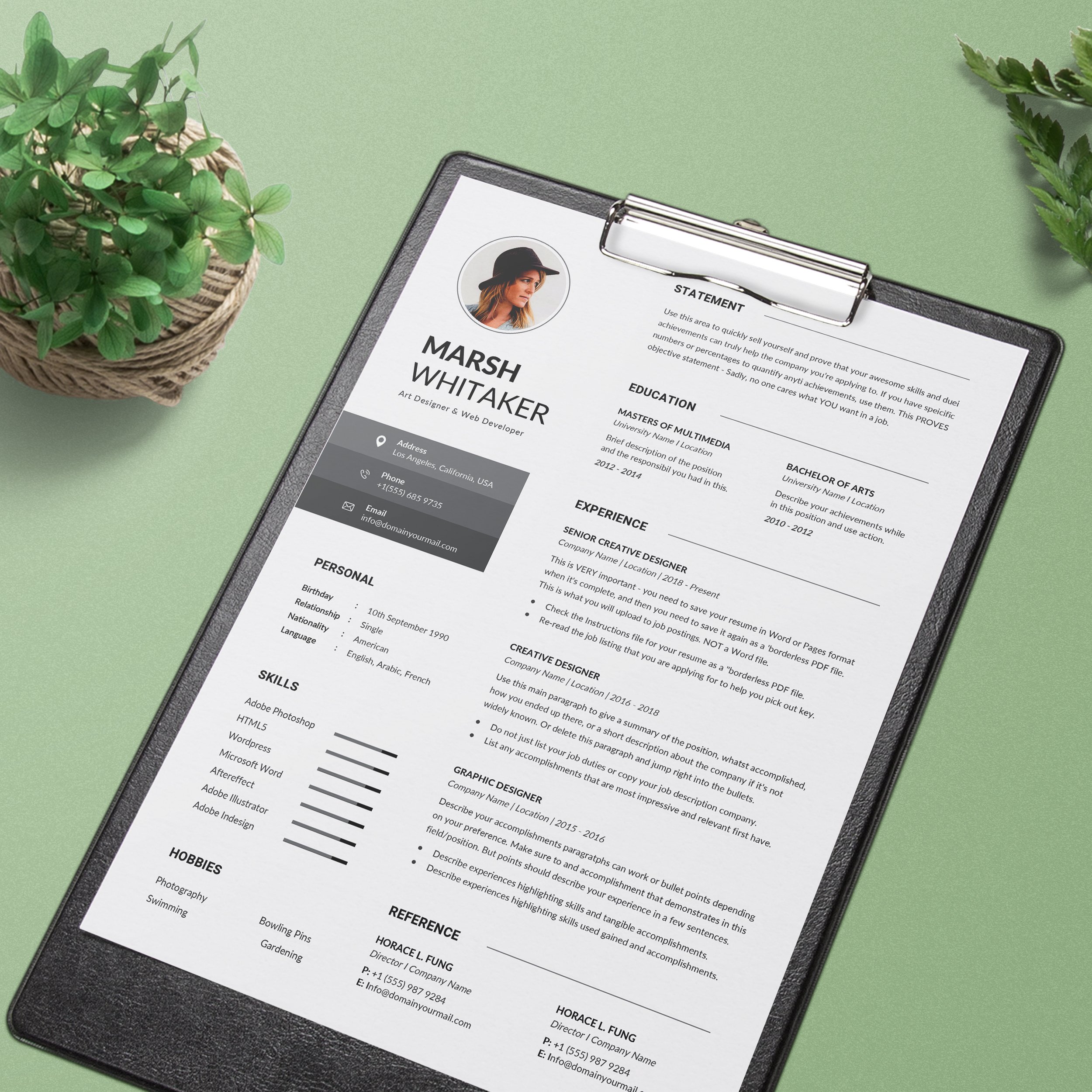 Black and white resume on a clipboard next to a potted plant.