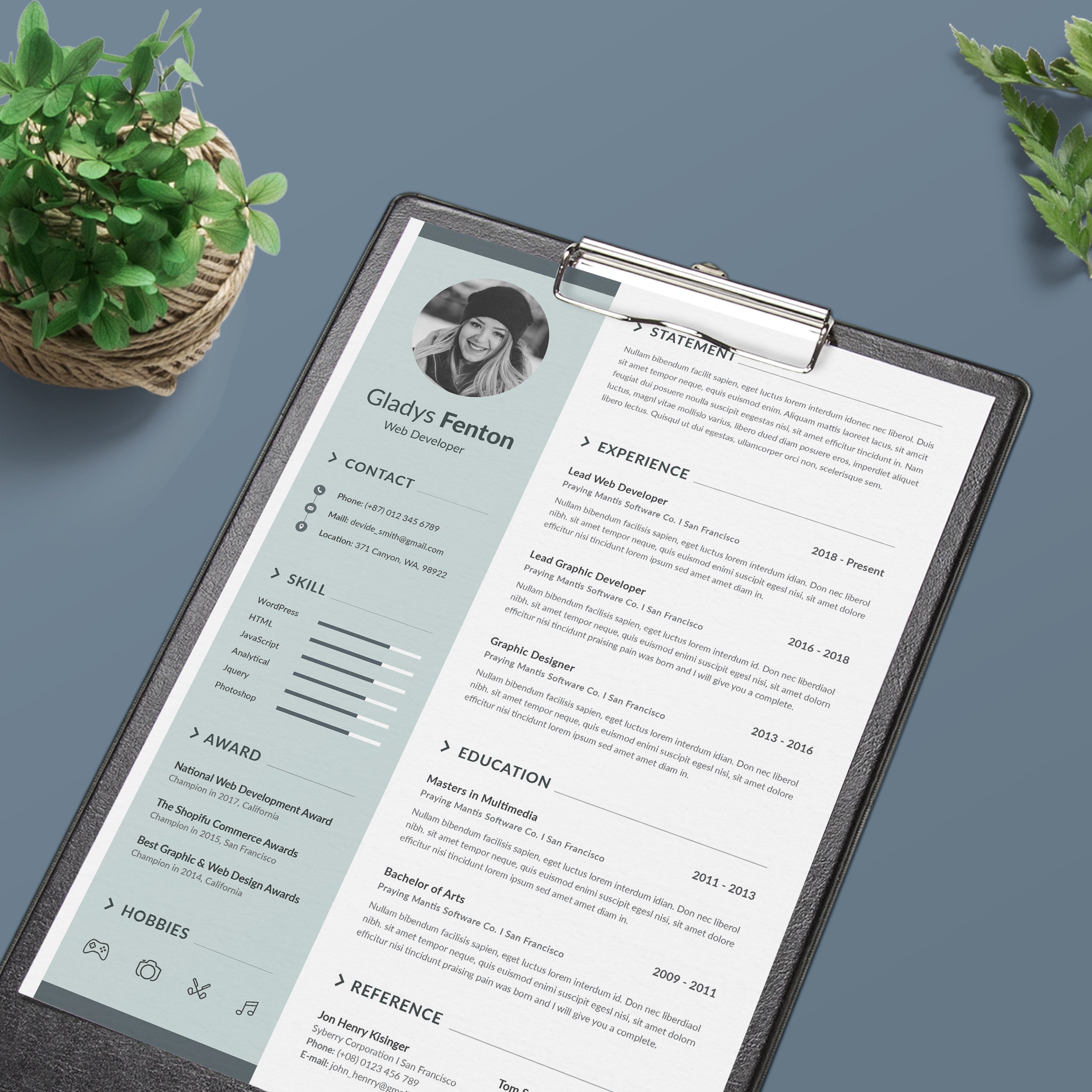 Resume on a clipboard next to a potted plant.