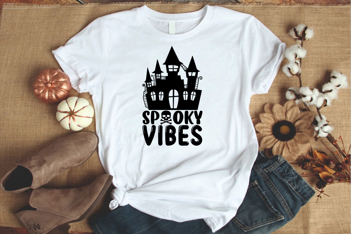 White t - shirt with a black spooky vibes castle on it.