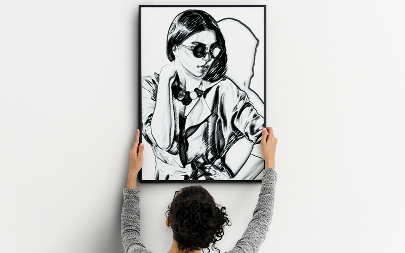 Woman holding up a black and white drawing of a woman.