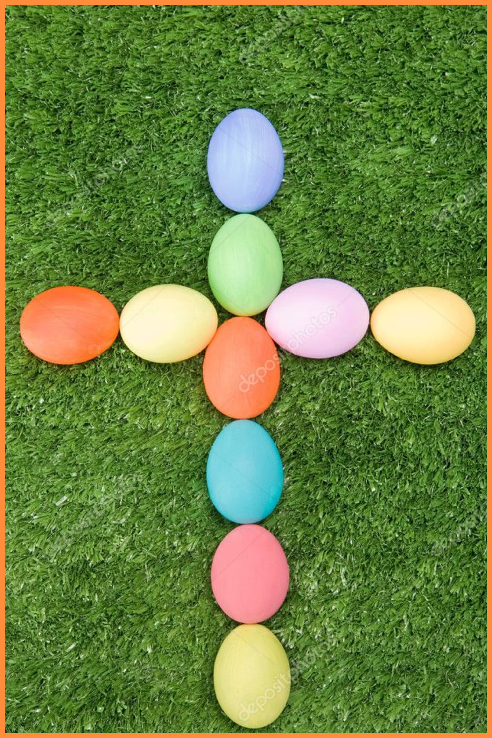 Cross made of colorful eggs on the grass.