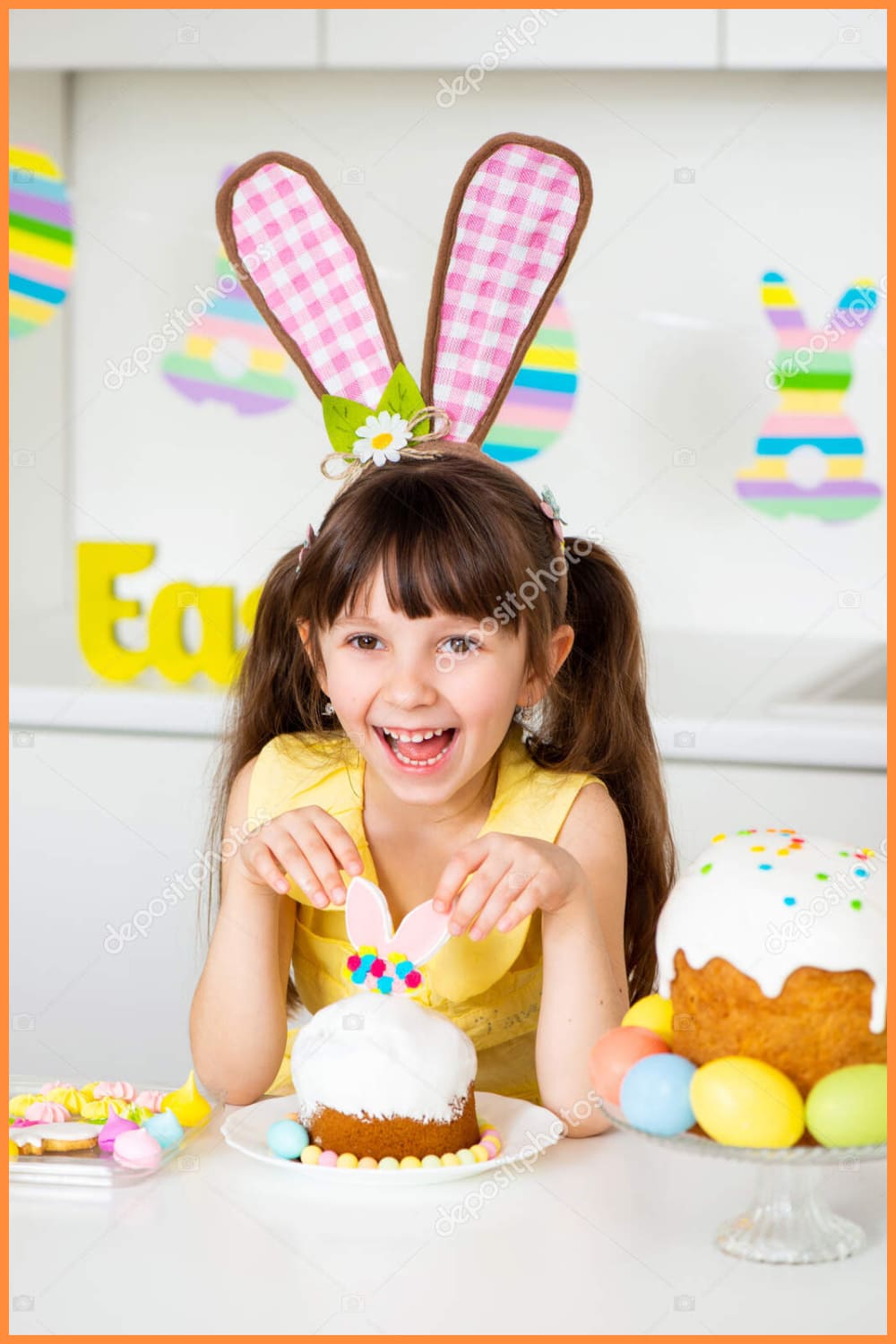 A cute smiling little girl with bunny ears prepares an Easter cake and painted eggs.