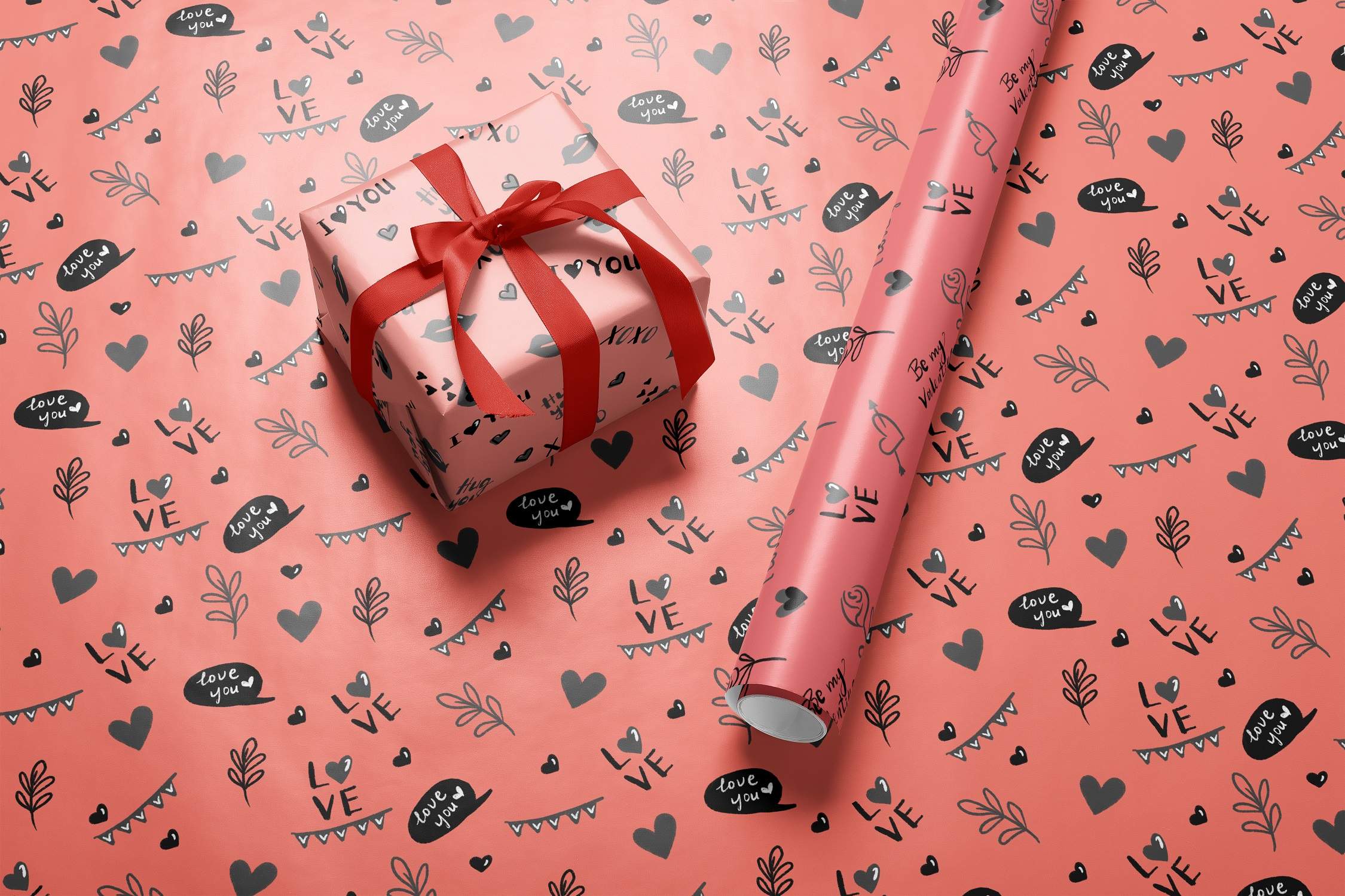 Present wrapped in a red ribbon next to a pink wrapping paper.