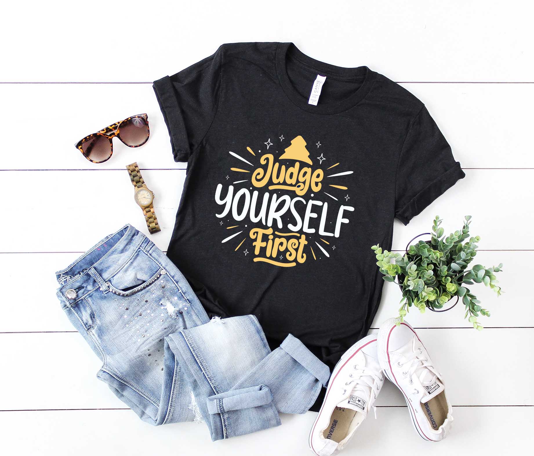 T - shirt that says judge yourself first next to a pair of jeans and.