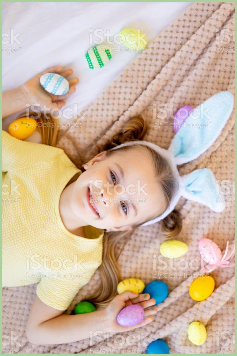 a little child girl among painted colored eggs is preparing for the holiday smiling and having fun.