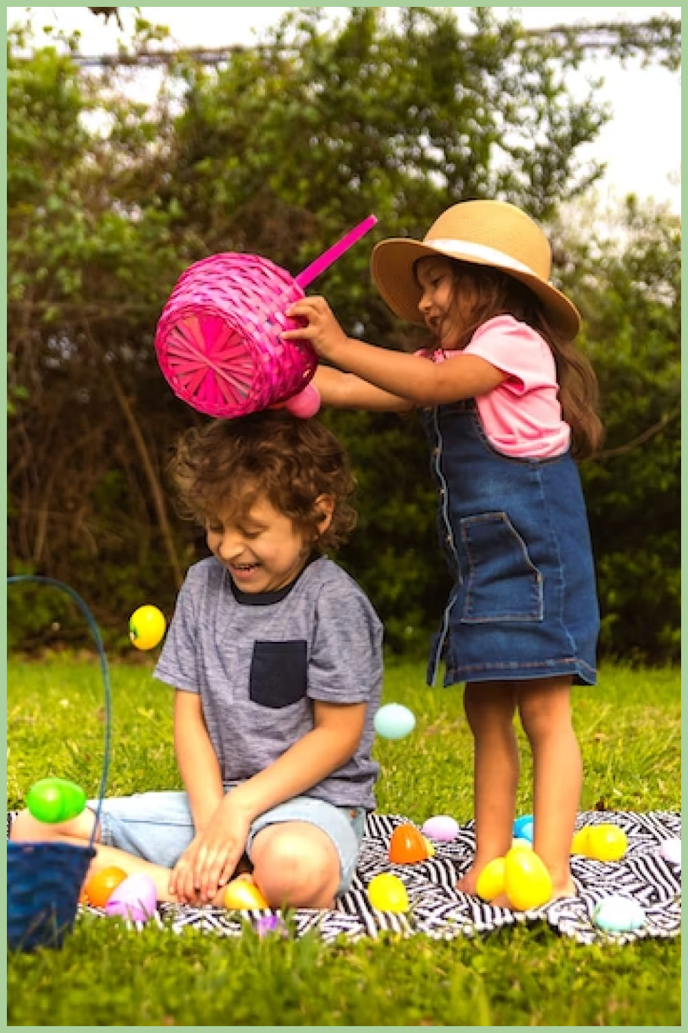 A boy sits on a mat and a girl stands over him with a pink basket.
