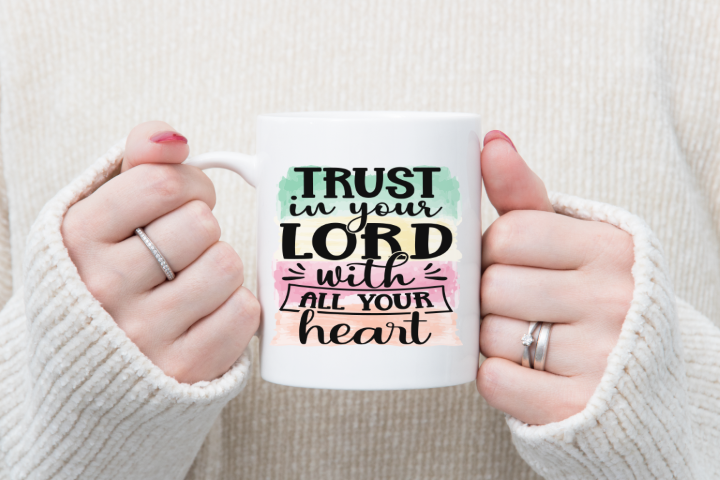 Woman holding a coffee mug that says trust in your lord with all your heart.