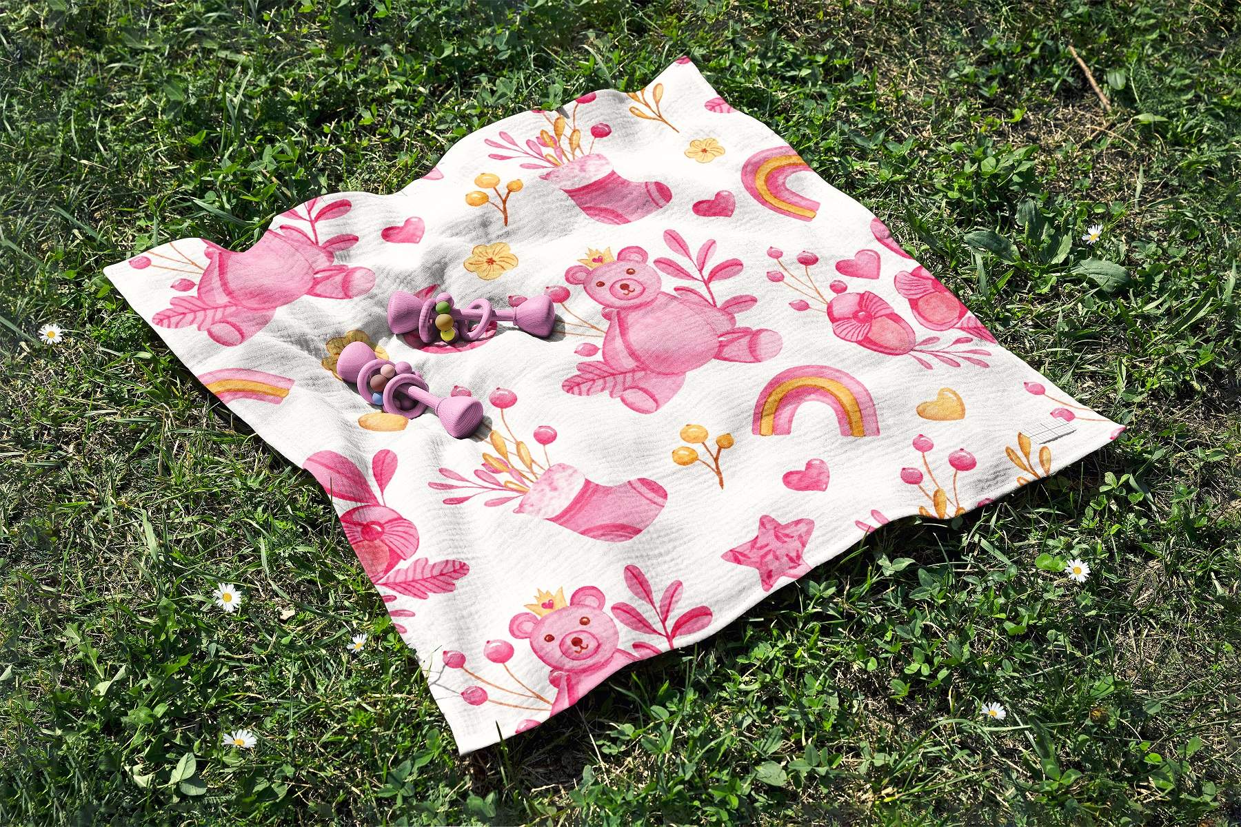 Pink and white blanket laying on top of a lush green field.
