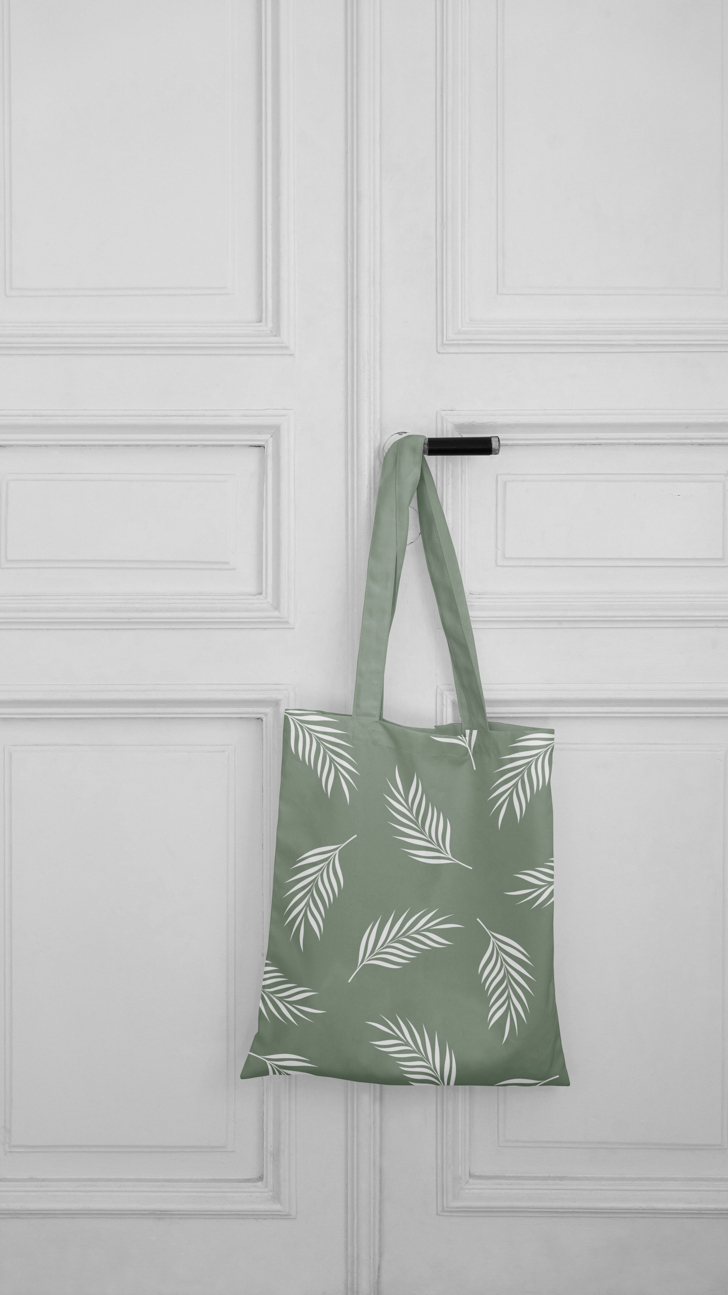 Green tote bag hanging on a white door.