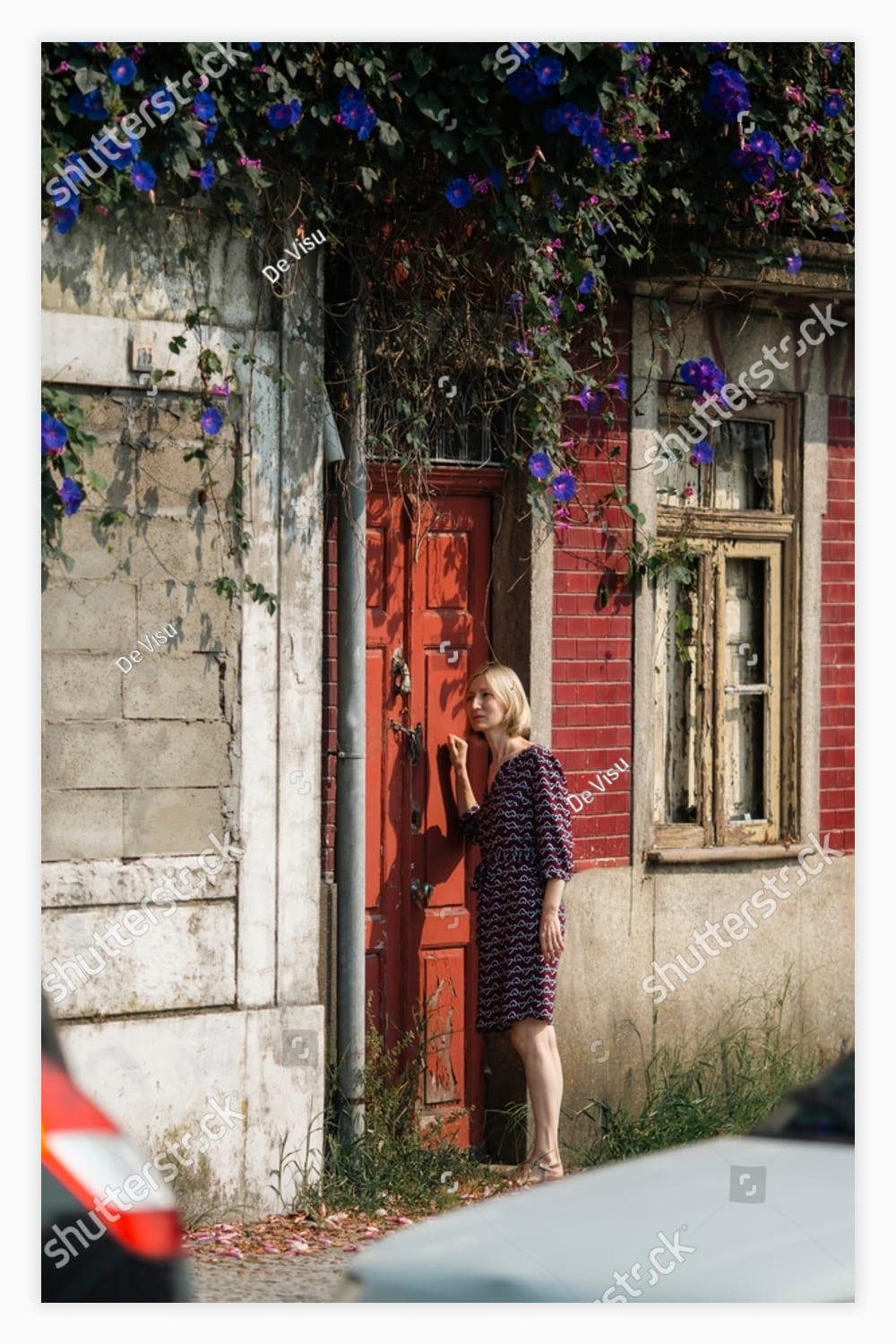 A woman stands outside the door of an abandoned house.