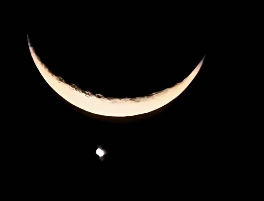 Crescent moon is seen in the dark sky.