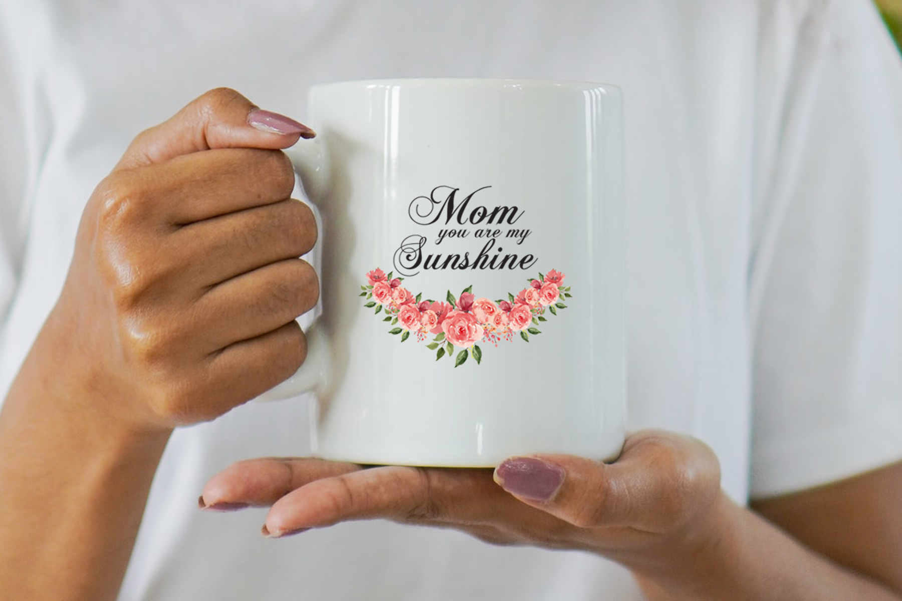Woman holding a white coffee mug with pink flowers.
