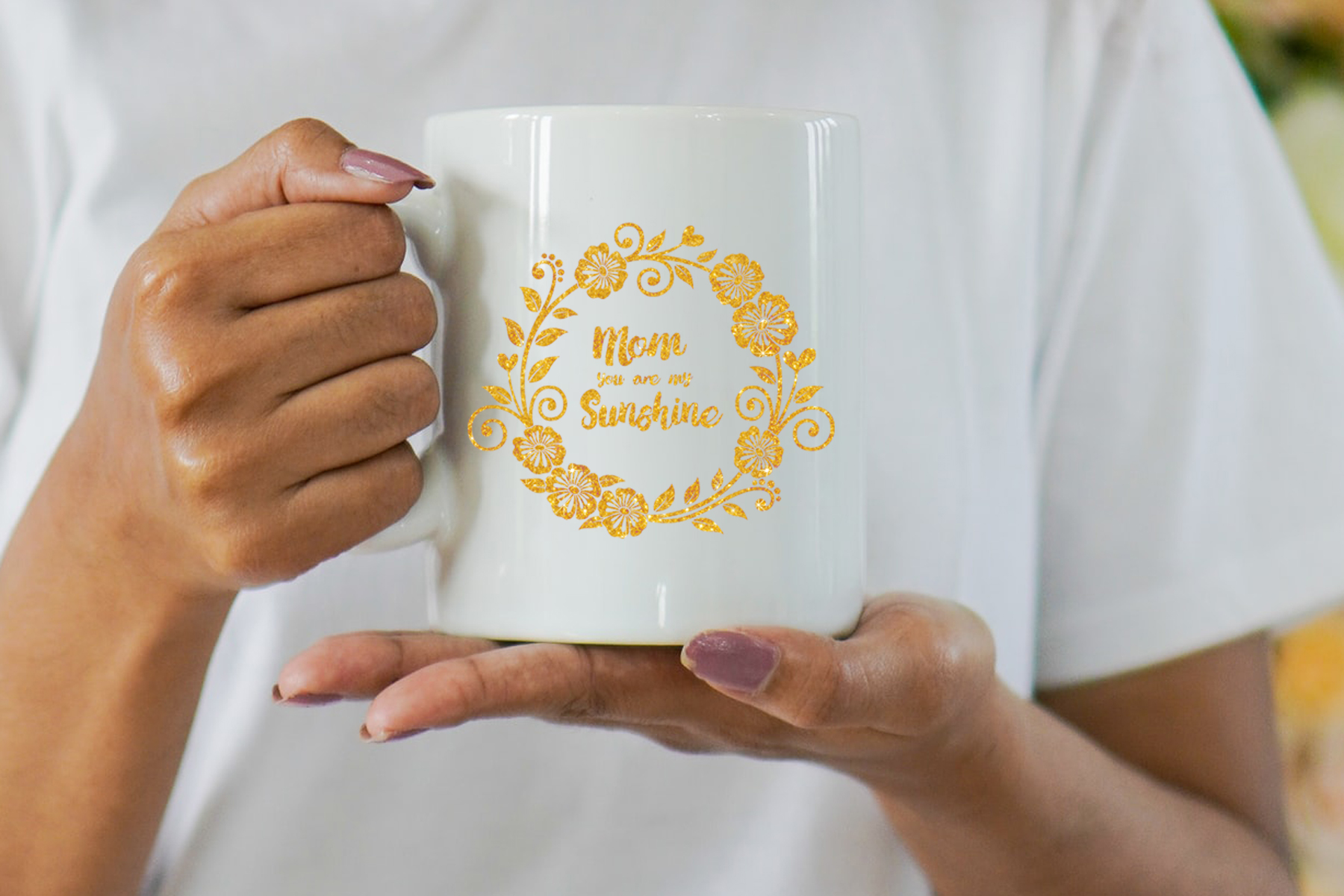 Woman holding a white coffee mug with yellow lettering.