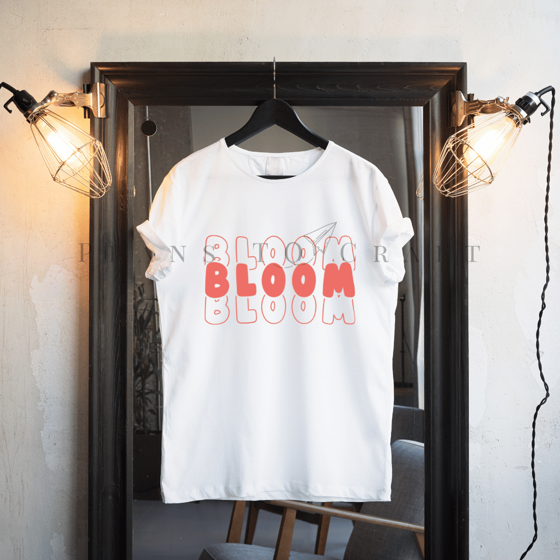 T - shirt that says bloom bloom on it hangs in front of a mirror.