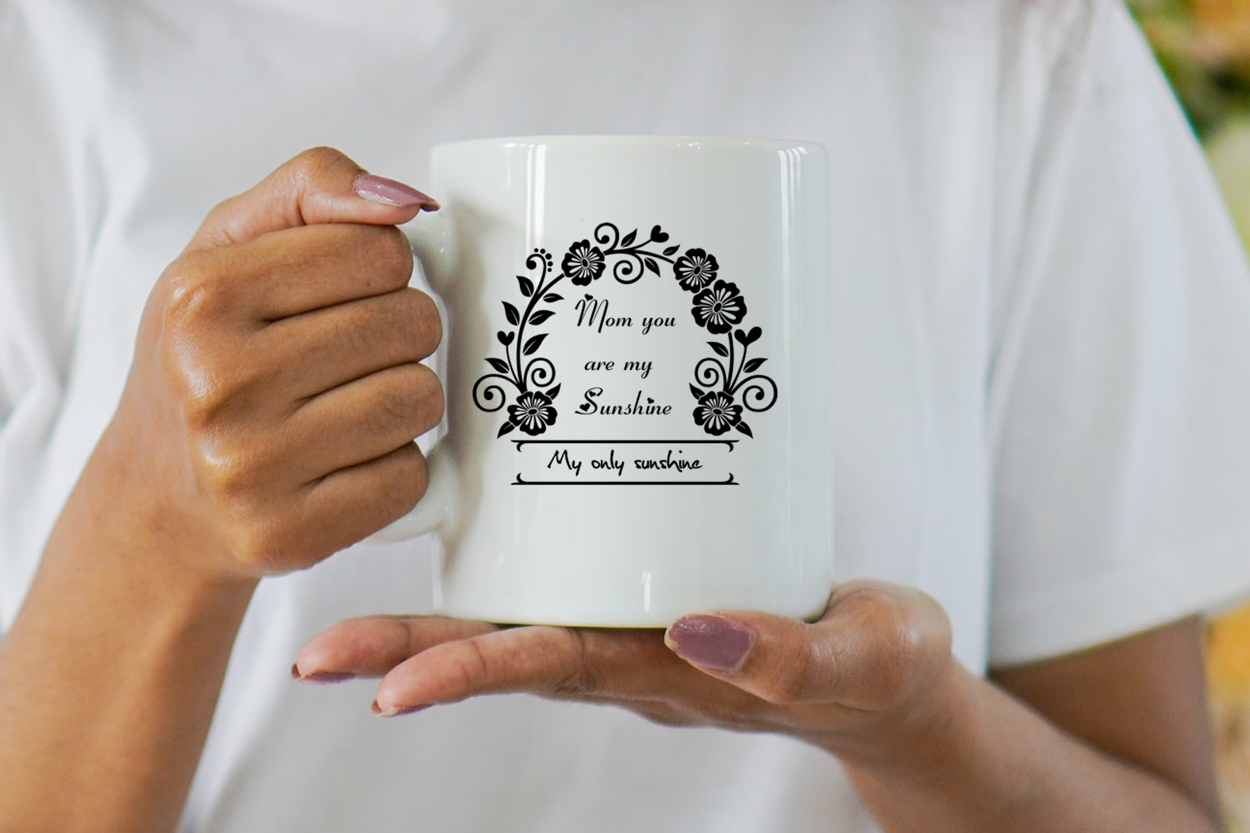 Woman holding a white coffee mug with a floral design.