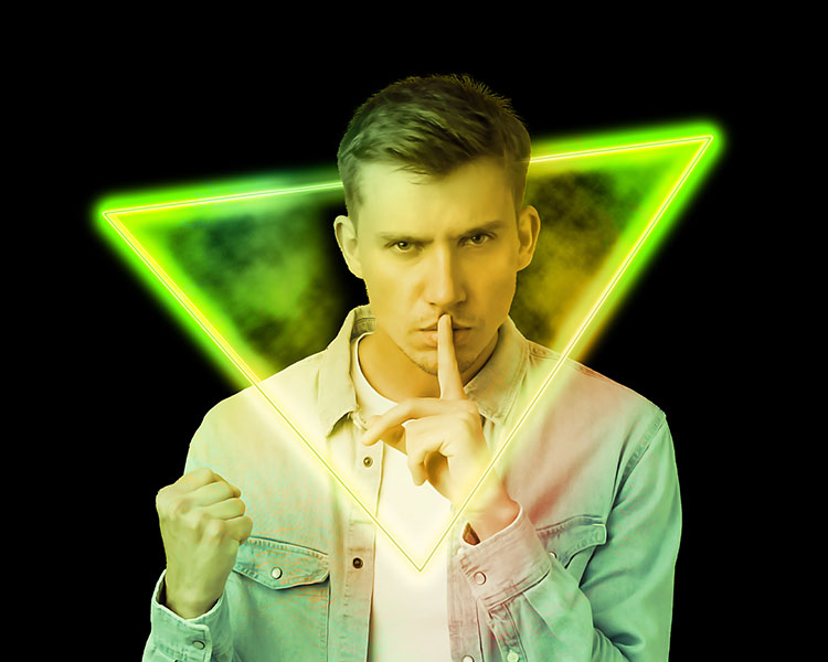 Man with a finger in his mouth standing in front of a neon triangle.