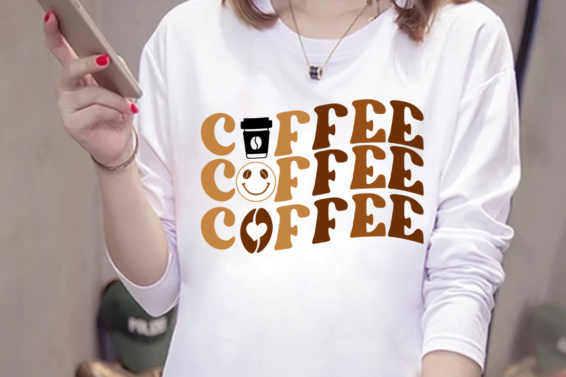 Woman holding a smart phone while wearing a coffee shirt.