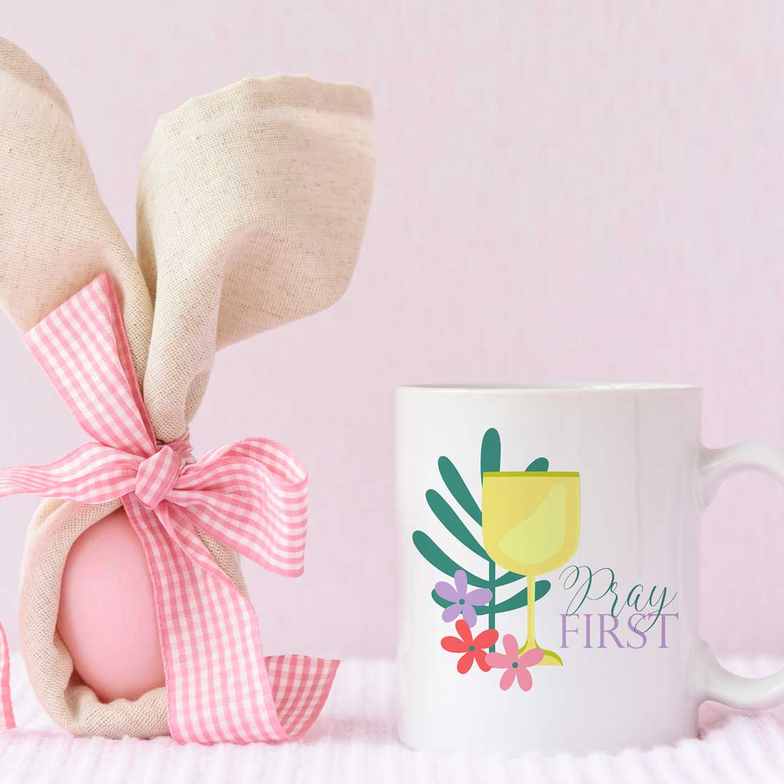 Coffee mug with a pink ribbon tied around it.