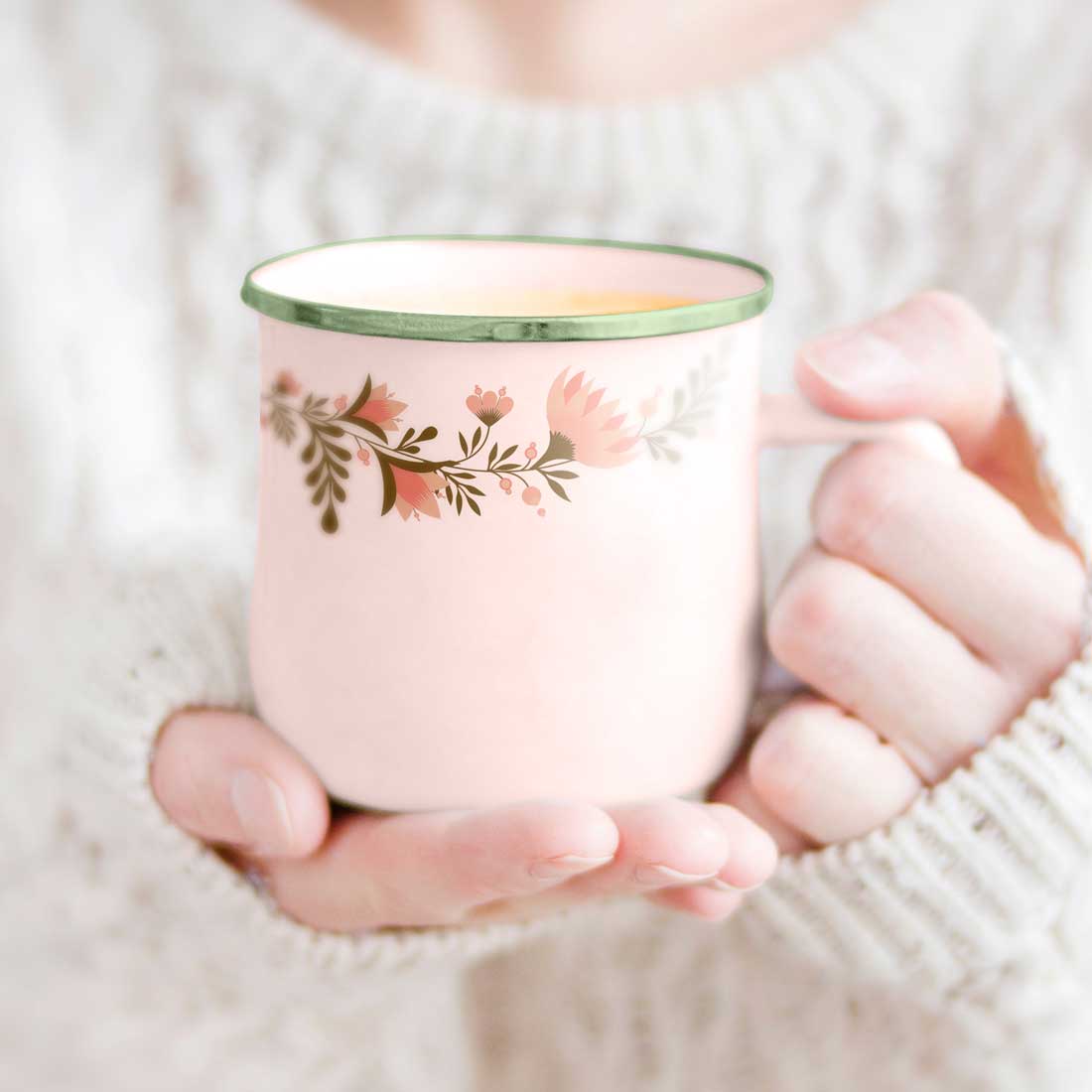 Woman holding a pink coffee mug in her hands.
