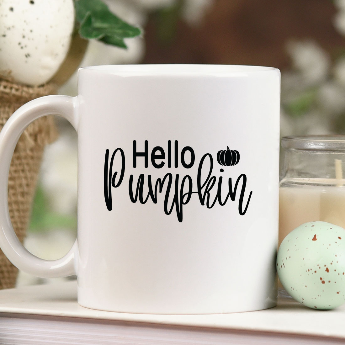 White coffee mug sitting on top of a table next to a candle.