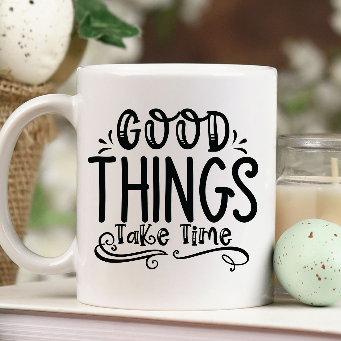 White coffee mug sitting on top of a table next to a candle.