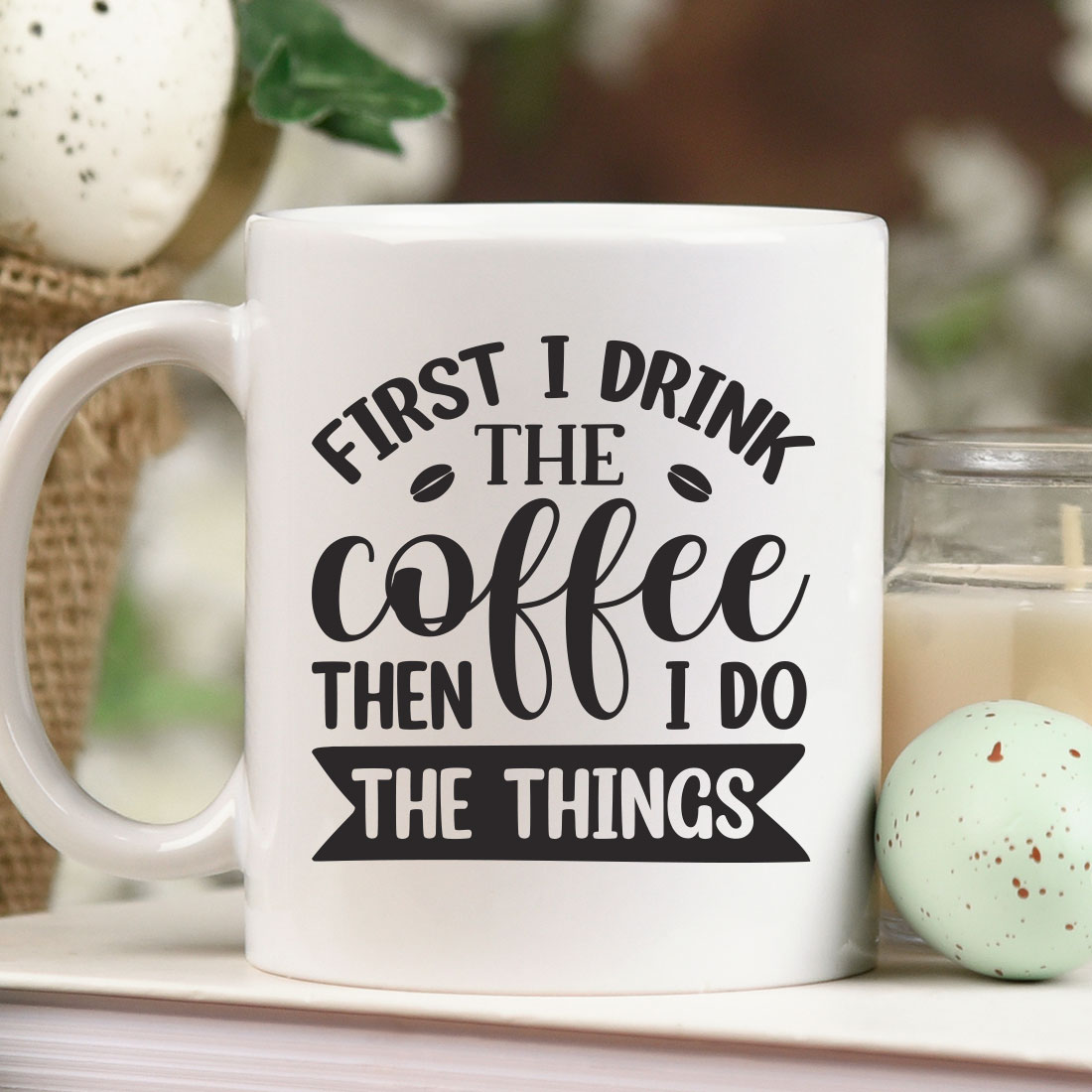 Coffee mug sitting on top of a table next to a candle.