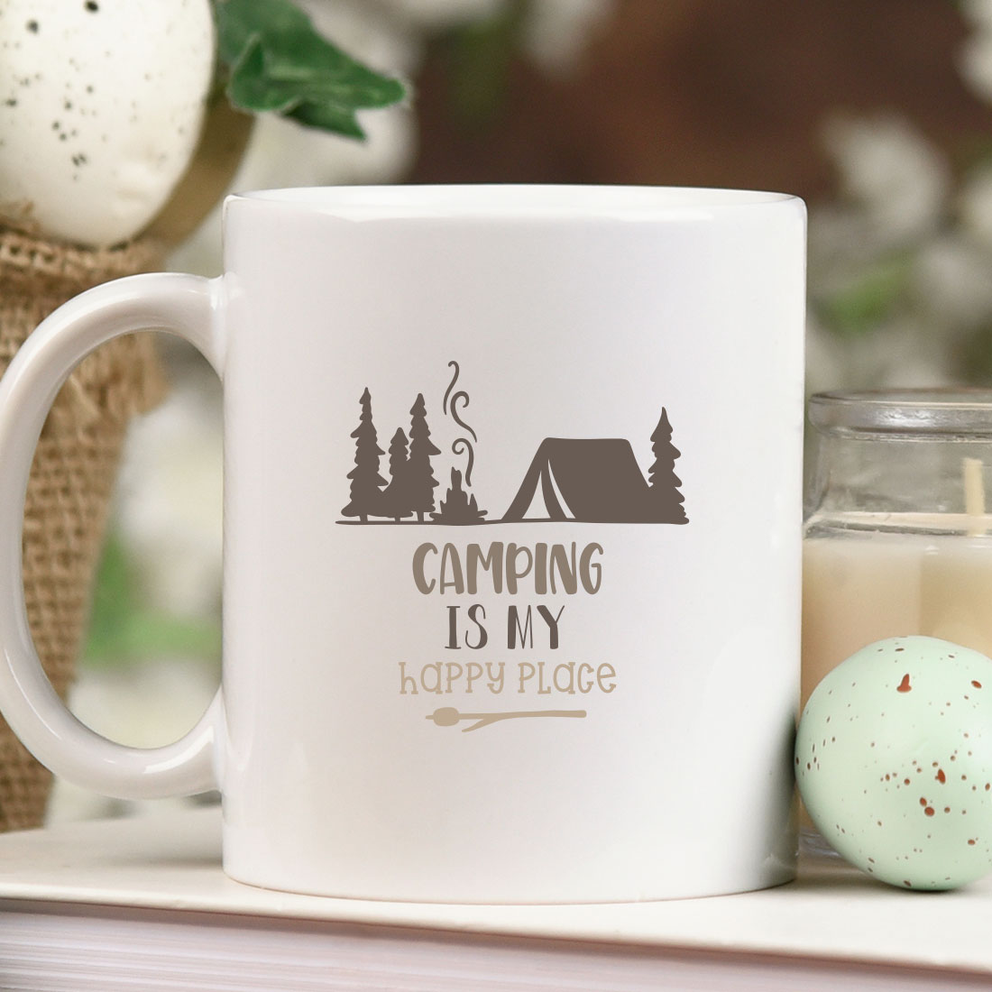 White coffee mug sitting on top of a table next to a candle.