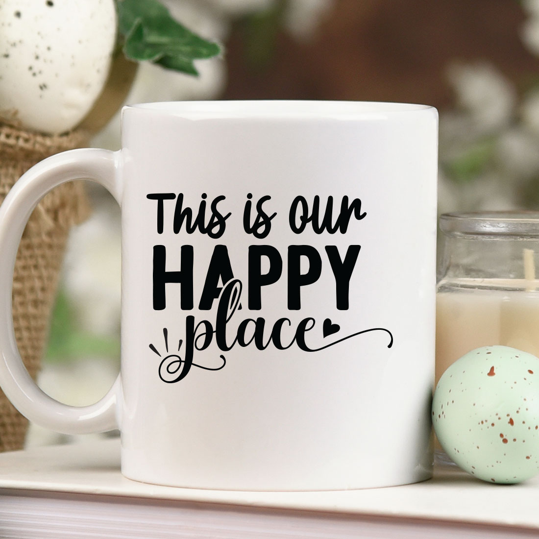 White coffee mug sitting on top of a table next to a candle.