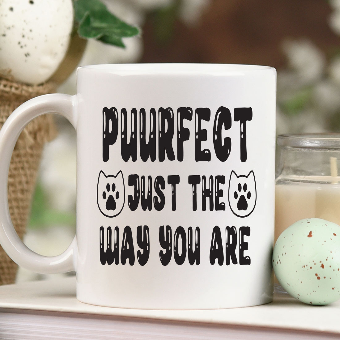 Coffee mug that says purrect just the way you are next to a.