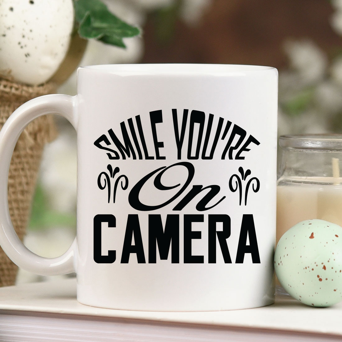 White coffee mug sitting on top of a table next to a candle.