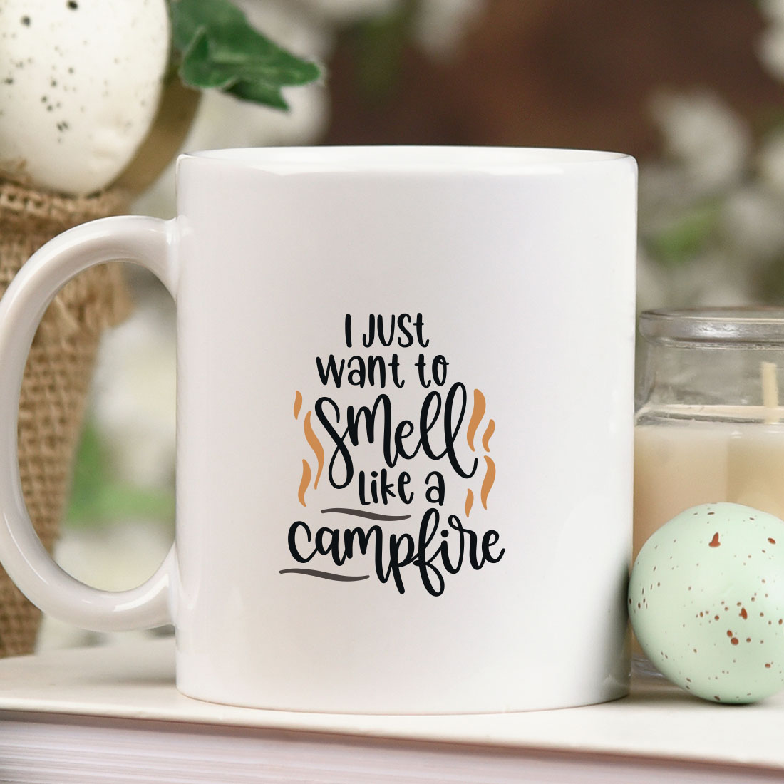 White coffee mug sitting on top of a table next to a candle.