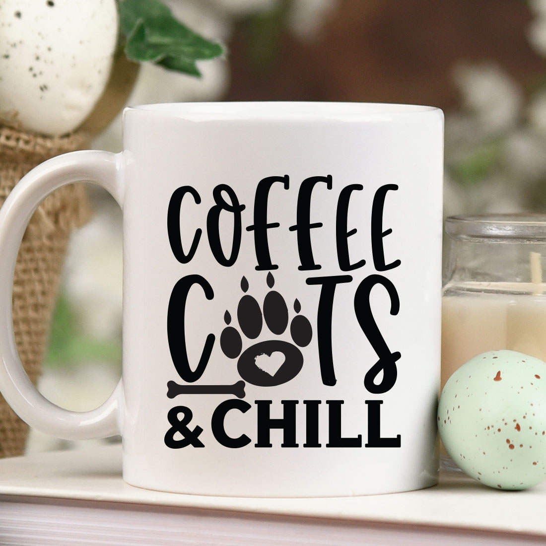 Coffee mug with the words coffee cats and chill on it next to a candle.