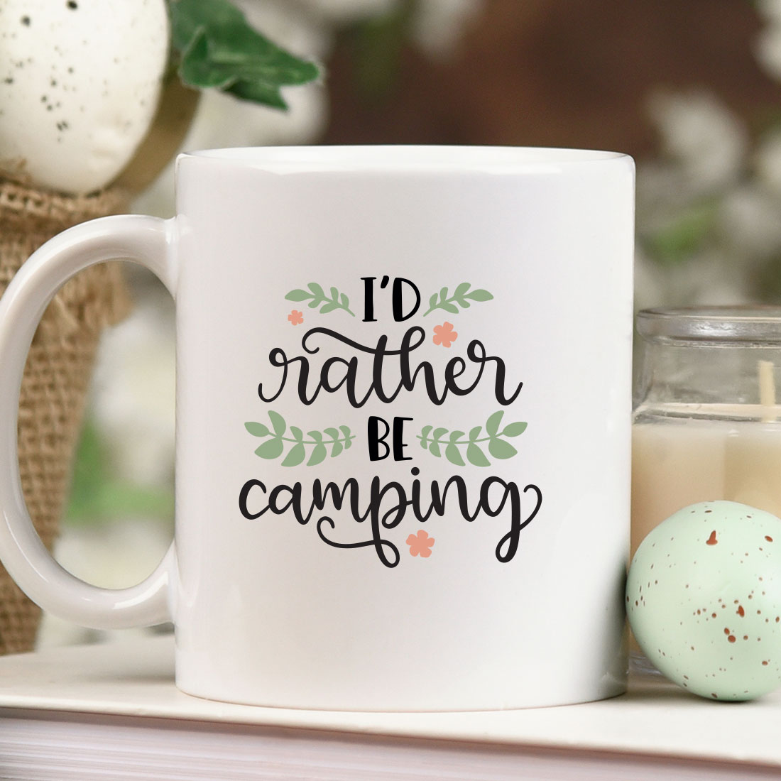 White coffee mug sitting on top of a table next to a candle.