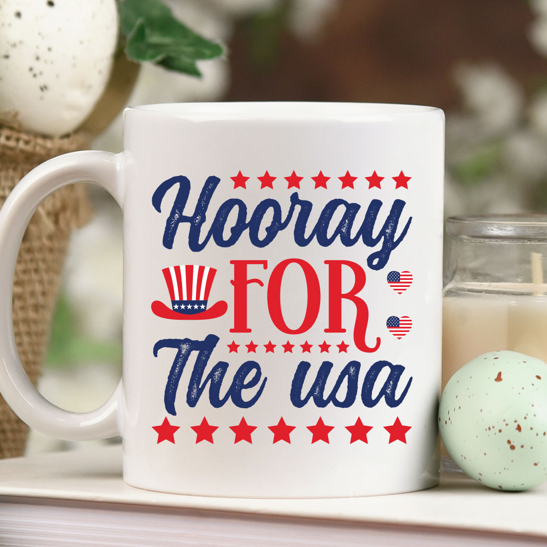 Coffee mug with the words hooray for the usa next to a candle.