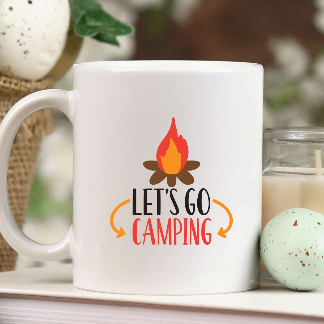 Coffee mug sitting on top of a table next to a candle.