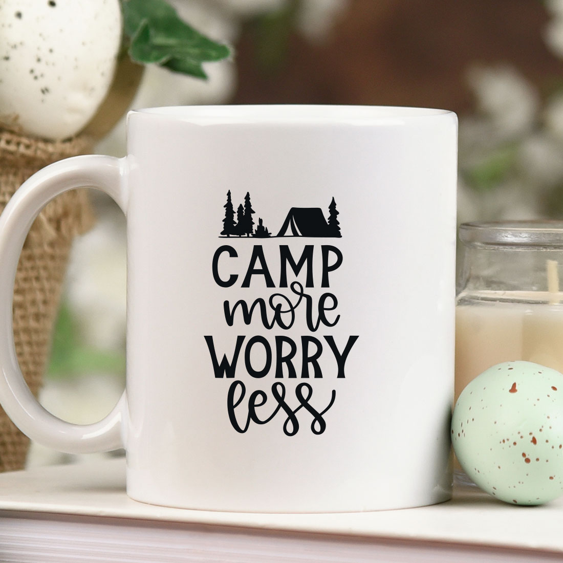 Coffee mug sitting on top of a table next to a candle.