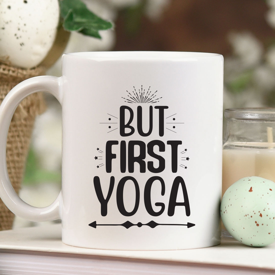 Coffee mug that says but first yoga next to a candle.