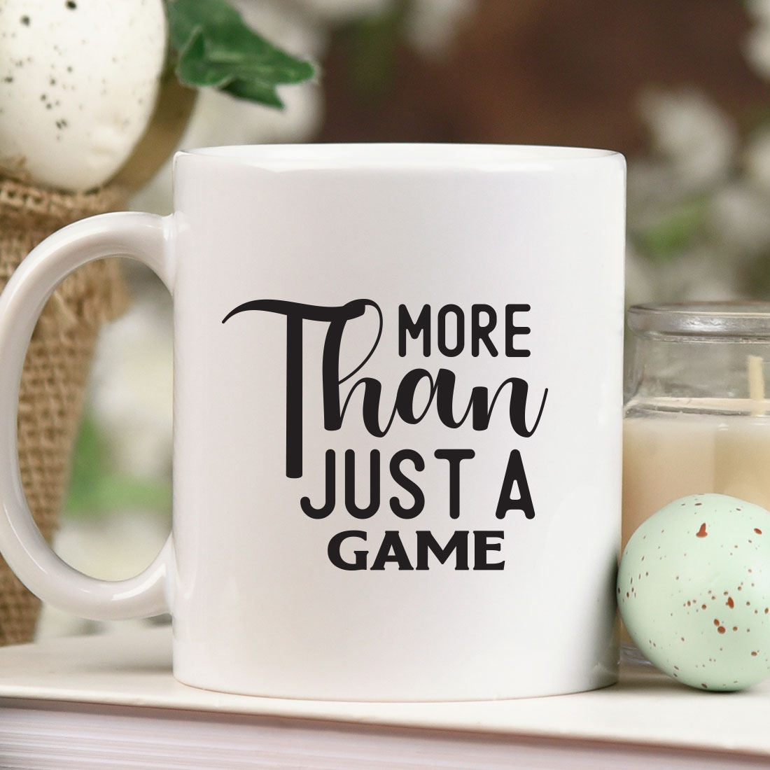 Coffee mug that says more than just a game next to a candle.