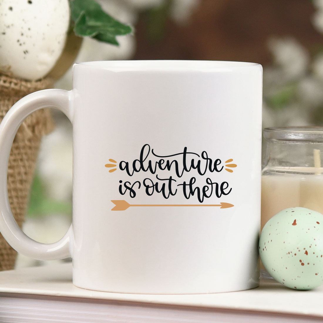 White coffee mug sitting on top of a table next to a candle.