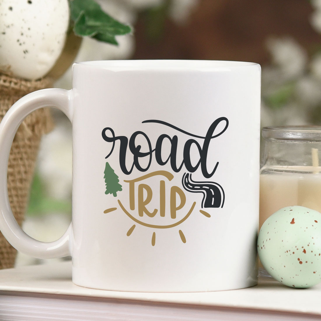 Coffee mug sitting on top of a table next to a candle.