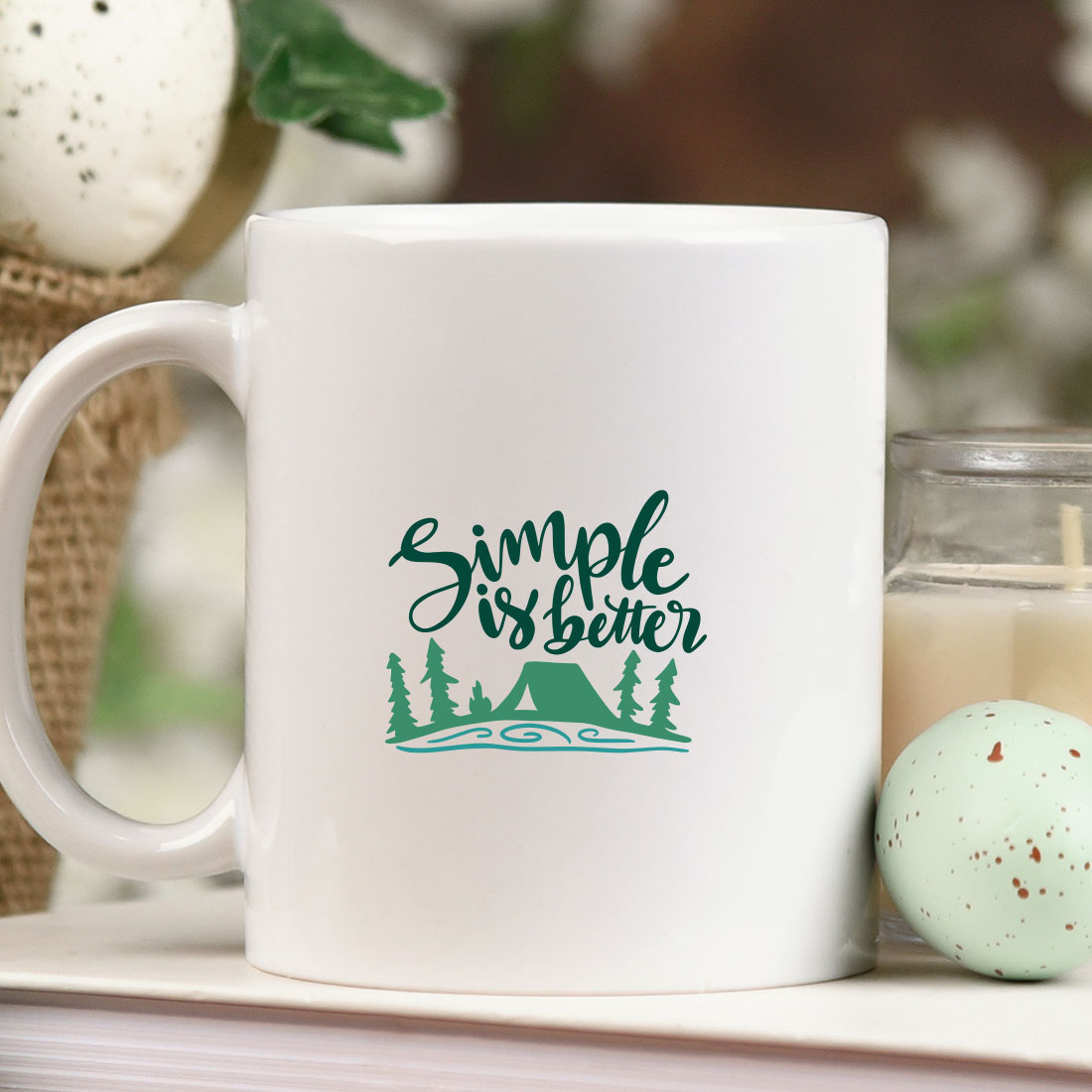 White coffee mug sitting on top of a table next to a candle.