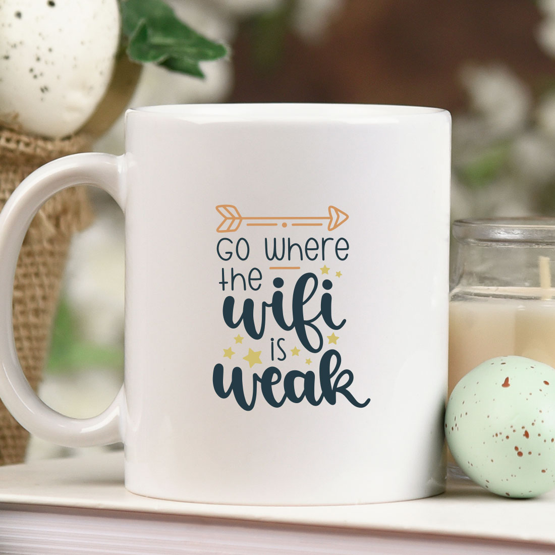 Coffee mug sitting on top of a table next to a candle.