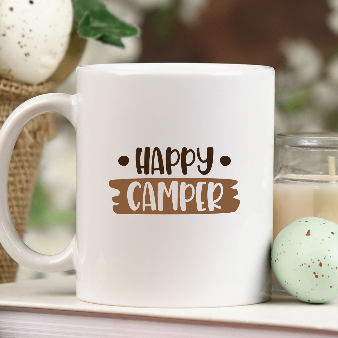 White coffee mug sitting on top of a table next to a candle.