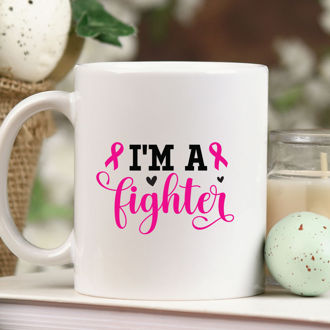 Coffee mug that says i'm a fighter next to a candle.