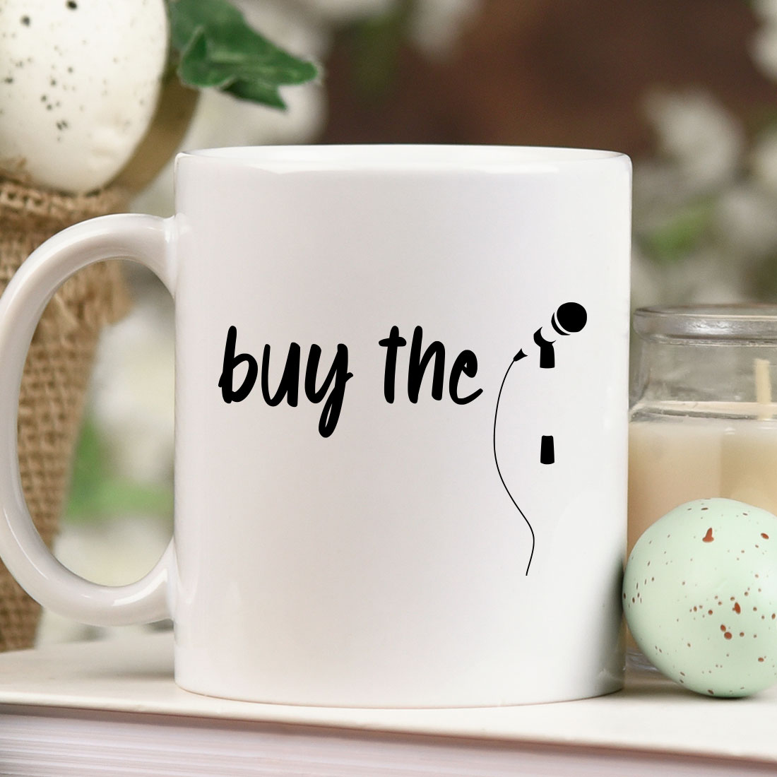 White coffee mug sitting on top of a table next to a candle.