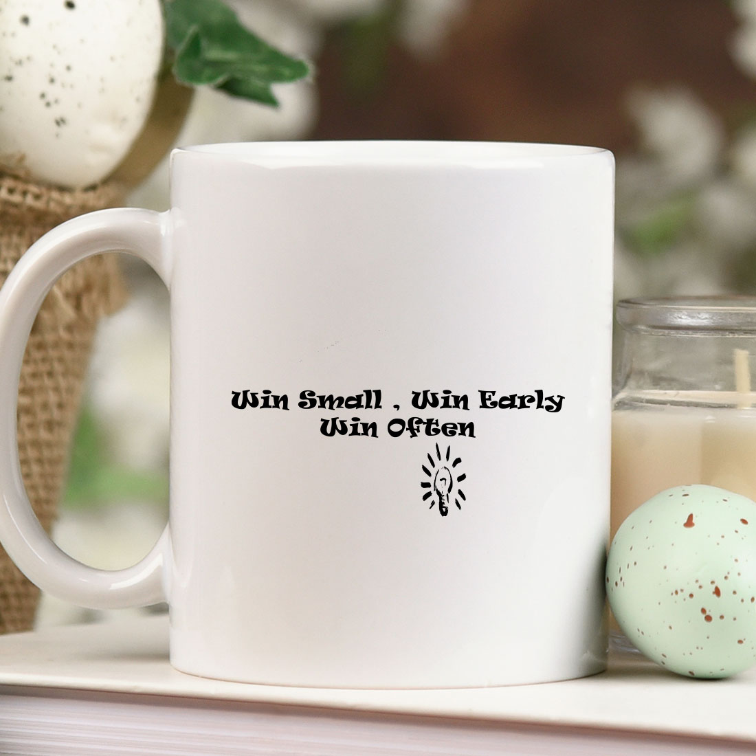 White coffee mug sitting on top of a table next to a candle.