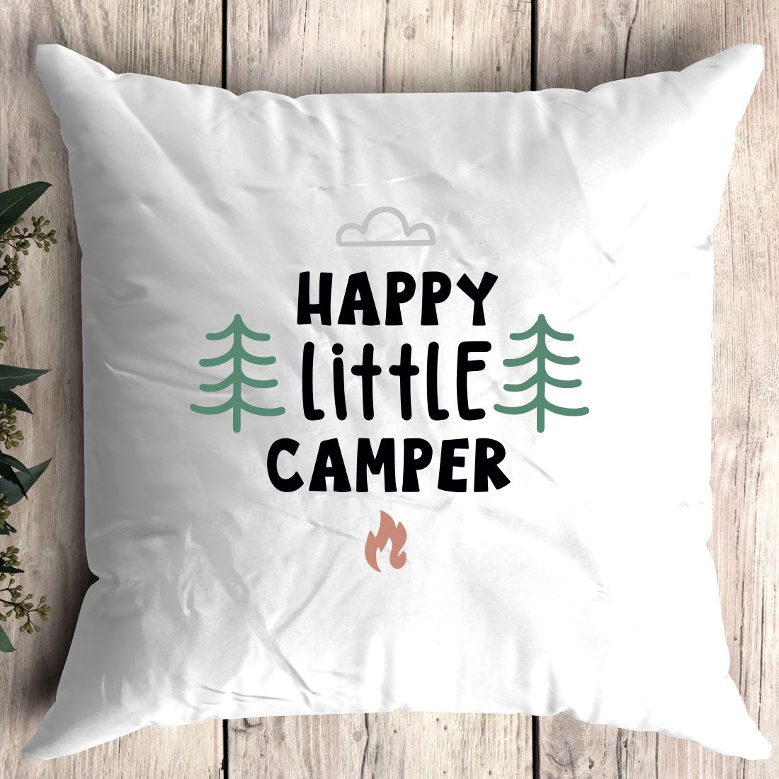 White pillow with the words happy little camper printed on it.