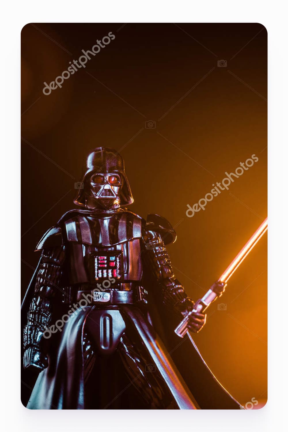 Darth Vader figurine with lightsaber on black background with shining sun.