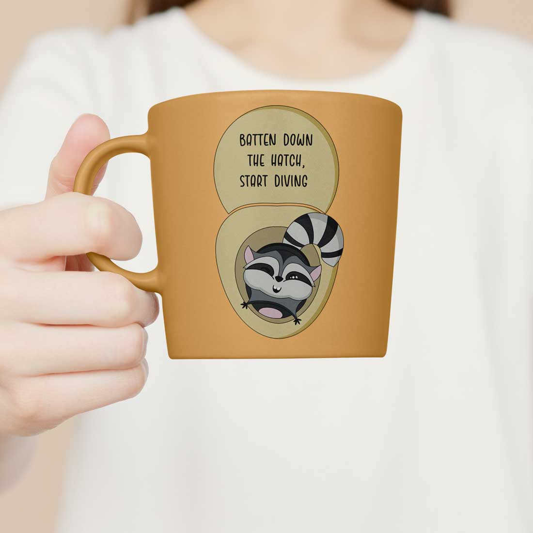 Woman holding a coffee mug with a raccoon on it.