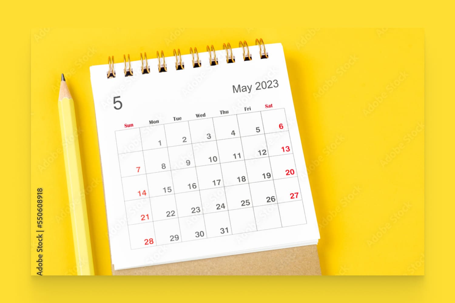 he May 2023 Monthly desk calendar for 2023 with pencil on yellow background.